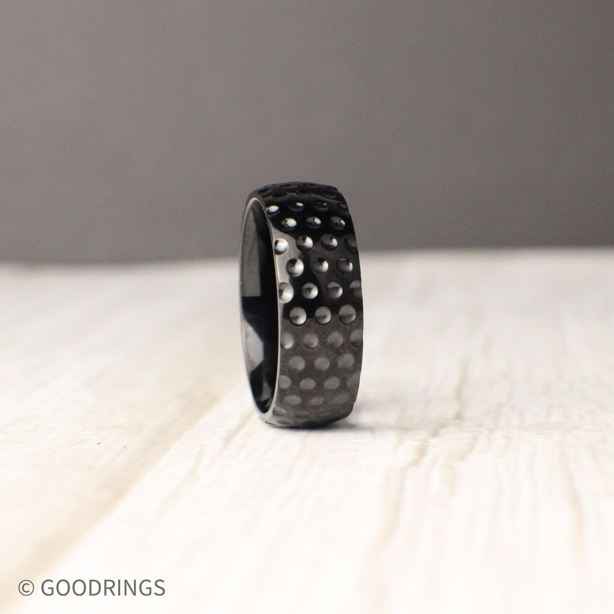 Titanium golf ball textured ring, 8mm wide comfort fit band featuring round dimples reminiscent of a golf ball surface, captured in detail to emphasize its sporty, rugged style, perfect for wedding bands, promise rings, or anniversary gifts that celebrate passion for the game and modern design.