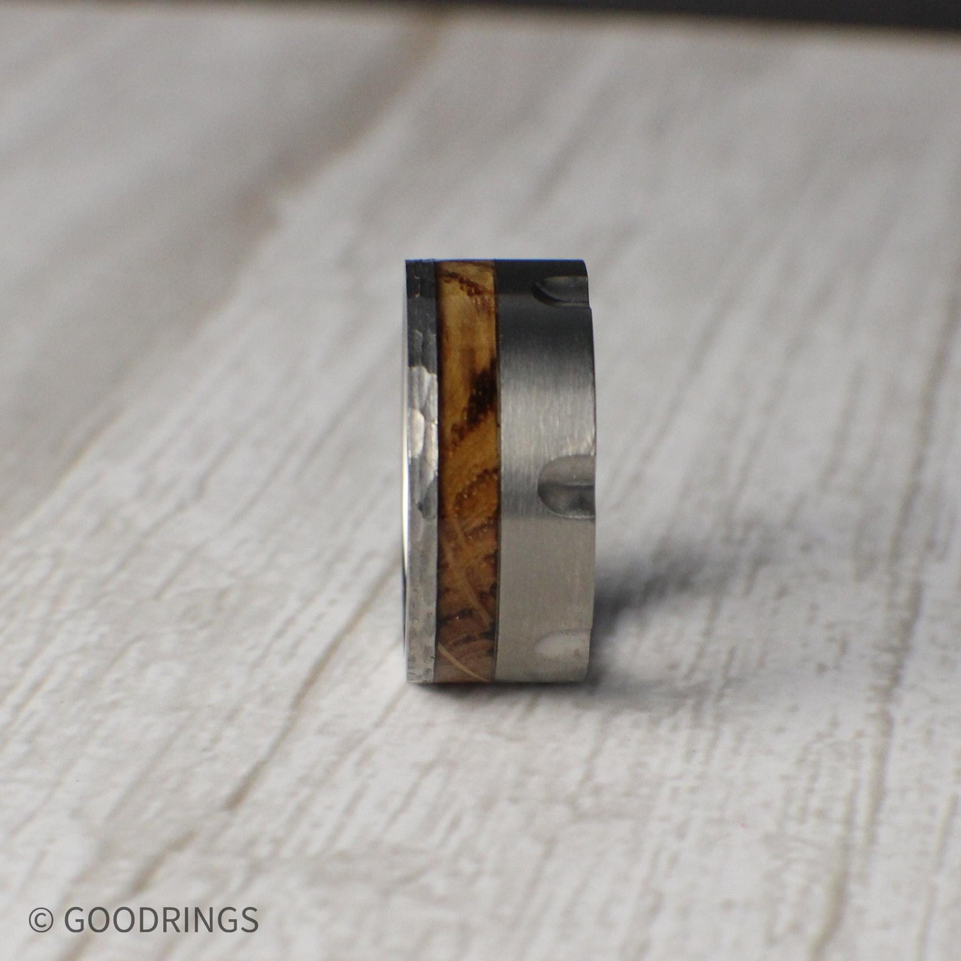 Masculine 10mm tungsten ring styled after the chamber of a revolver, featuring recessed grooves for a unique, rugged finish. A striking inlay of charred whiskey barrel wood runs through the band, symbolizing tradition and heritage while adding natural character. Perfect for weddings, anniversaries, or as a bold statement piece, this durable comfort-fit band combines grit, style, and individuality.