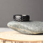 Unique 8mm wide titanium golf ball textured ring with a hammered-like dimple design across the surface, photographed in a rustic natural setting on stone and wood, perfect for couples looking for a durable and sporty wedding band or anniversary gift inspired by the game of golf.