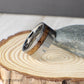 A bold 10mm tungsten ring crafted to capture the style of a revolver chamber, complete with recessed grooves that add toughness and depth. The inlay of charred whiskey barrel wood creates a warm, rustic contrast to the modern brushed tungsten. Durable, comfortable, and full of character, this ring is ideal for weddings, anniversaries, or anyone seeking a statement piece that blends heritage with strength.
