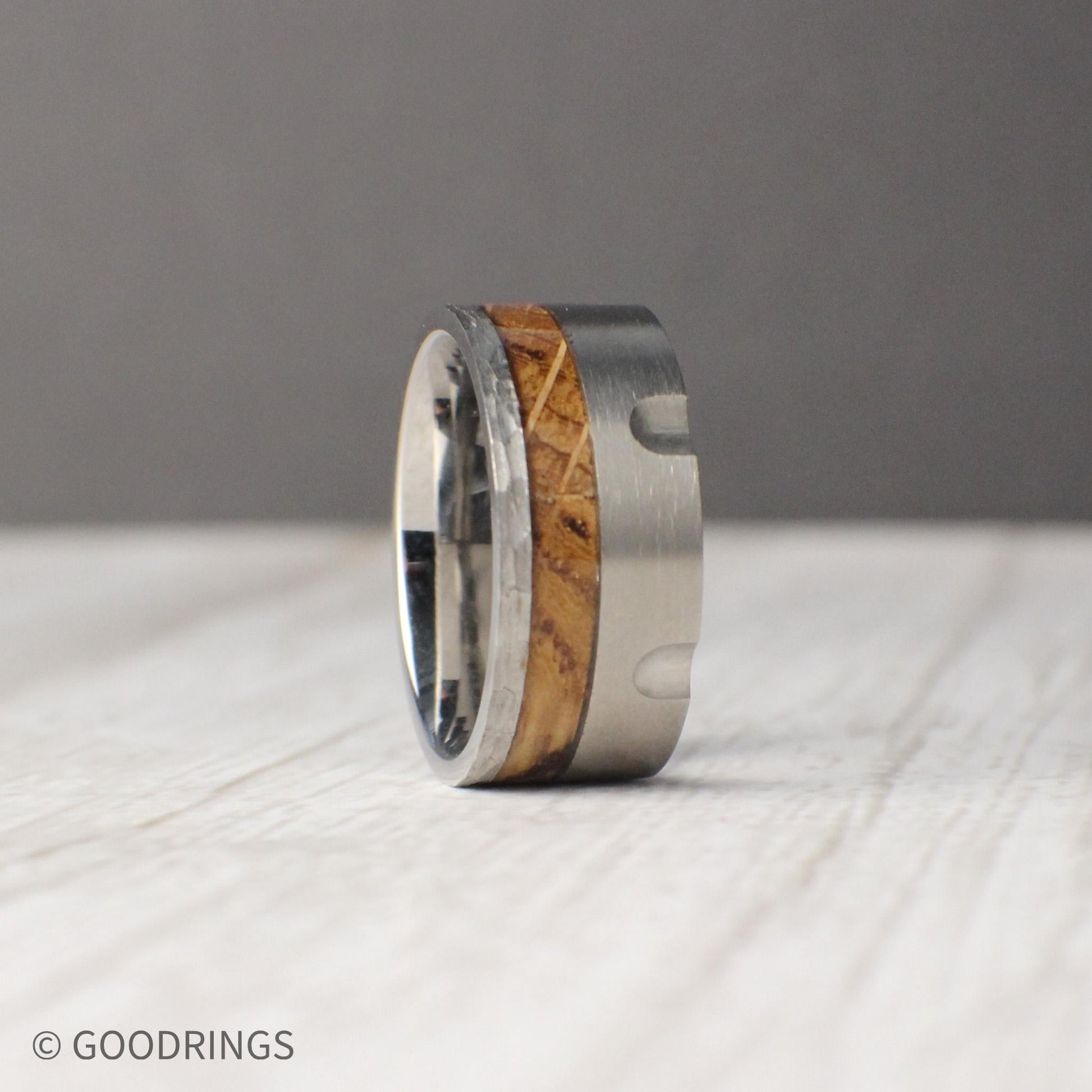 10mm tungsten wedding band inspired by the mechanical design of a revolver, featuring detailed grooves carved into the brushed metal band. The centerpiece is an inlay of charred whiskey barrel wood, showcasing natural texture and heritage against the sleek durability of tungsten. Rugged yet refined, this masculine ring makes a unique choice for weddings, anniversaries, or everyday wear.