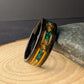 Close-up of tungsten men’s wedding ring featuring green opals, gold leaf details, and a whiskey barrel wood inlay