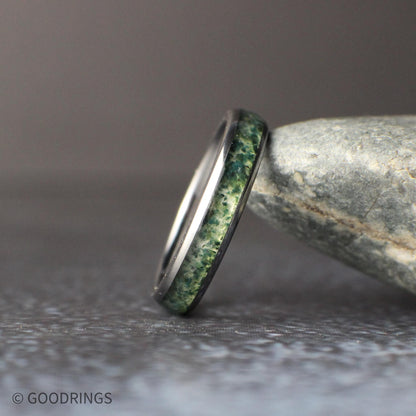 Modern couples ring set crafted from black tungsten, featuring an 8mm band with meteorite and moss agate inlays and a coordinating 4mm band with moss agate only. Soft lighting highlights the natural green tones of the agate and the textured metallic appearance of the meteorite, creating a cohesive his and hers wedding ring set.