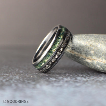 Matching his and hers tungsten wedding rings shown side by side. The 8mm ring features a bold combination of meteorite and moss agate inlays, while the slimmer 4mm ring showcases a clean moss agate inlay in a black core. The image emphasizes the contrast between organic stone textures and the sleek, durable tungsten design.