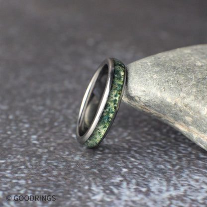 Couples matching wedding bands made from black tungsten. The men’s 8mm ring features a striking meteorite and moss agate inlay combination, while the women’s 4mm ring offers a refined moss agate inlay for a simpler look. The photo highlights the balance between bold texture and understated elegance in this nature-inspired ring set.