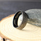 Flat lay image of a men's Hawaiian inspired wedding band with repeating geometric Polynesian pattern engraved into black tungsten. The seamless design continues around the band representing eternity and connection.