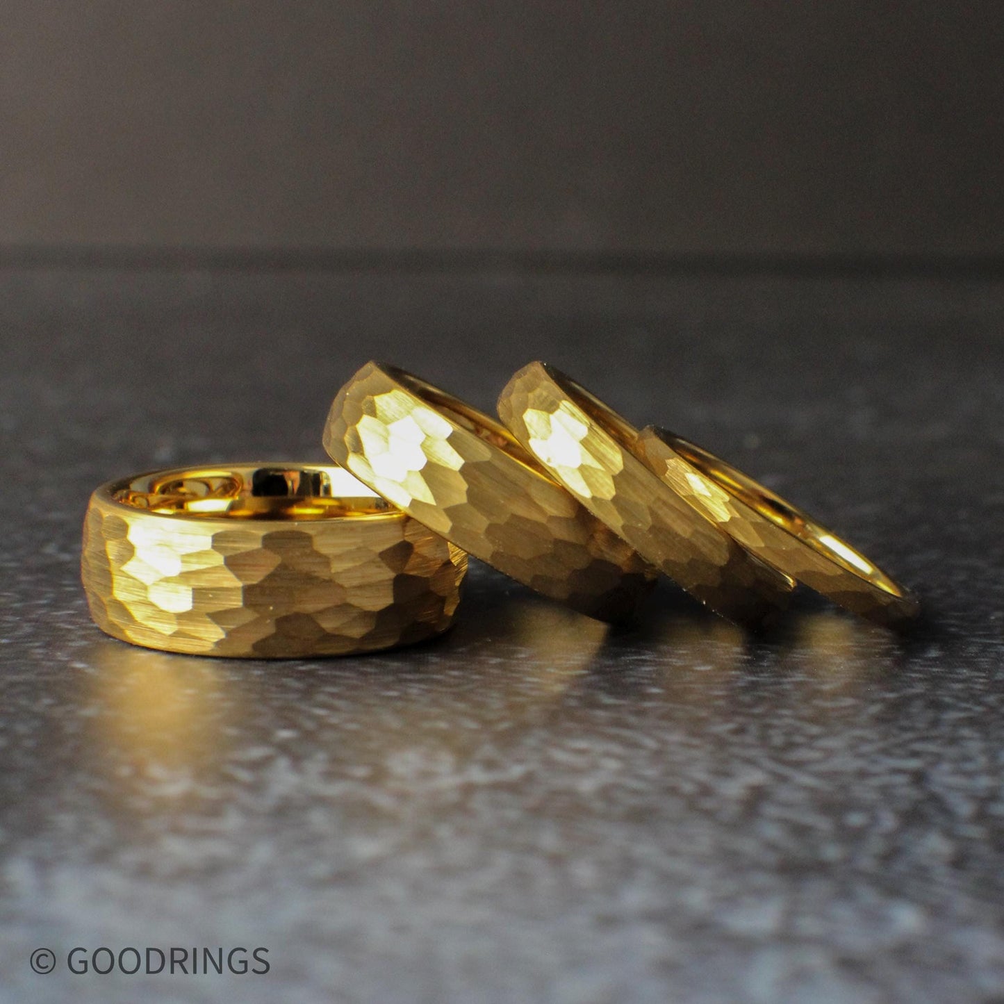 Stack of gold hammered tungsten rings arranged to highlight the variety of widths and consistent textured finish. These rings are ideal for wedding sets, couple bands, or anyone looking for a durable gold ring with a unique, eye-catching surface.