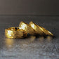 Stack of gold hammered tungsten rings arranged to highlight the variety of widths and consistent textured finish. These rings are ideal for wedding sets, couple bands, or anyone looking for a durable gold ring with a unique, eye-catching surface.