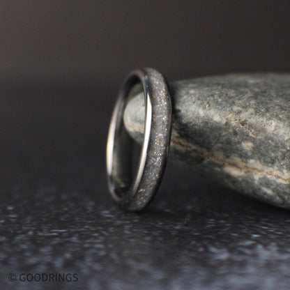 4mm tungsten ring with crushed moonstone inlay standing upright against a natural stone background with soft lighting