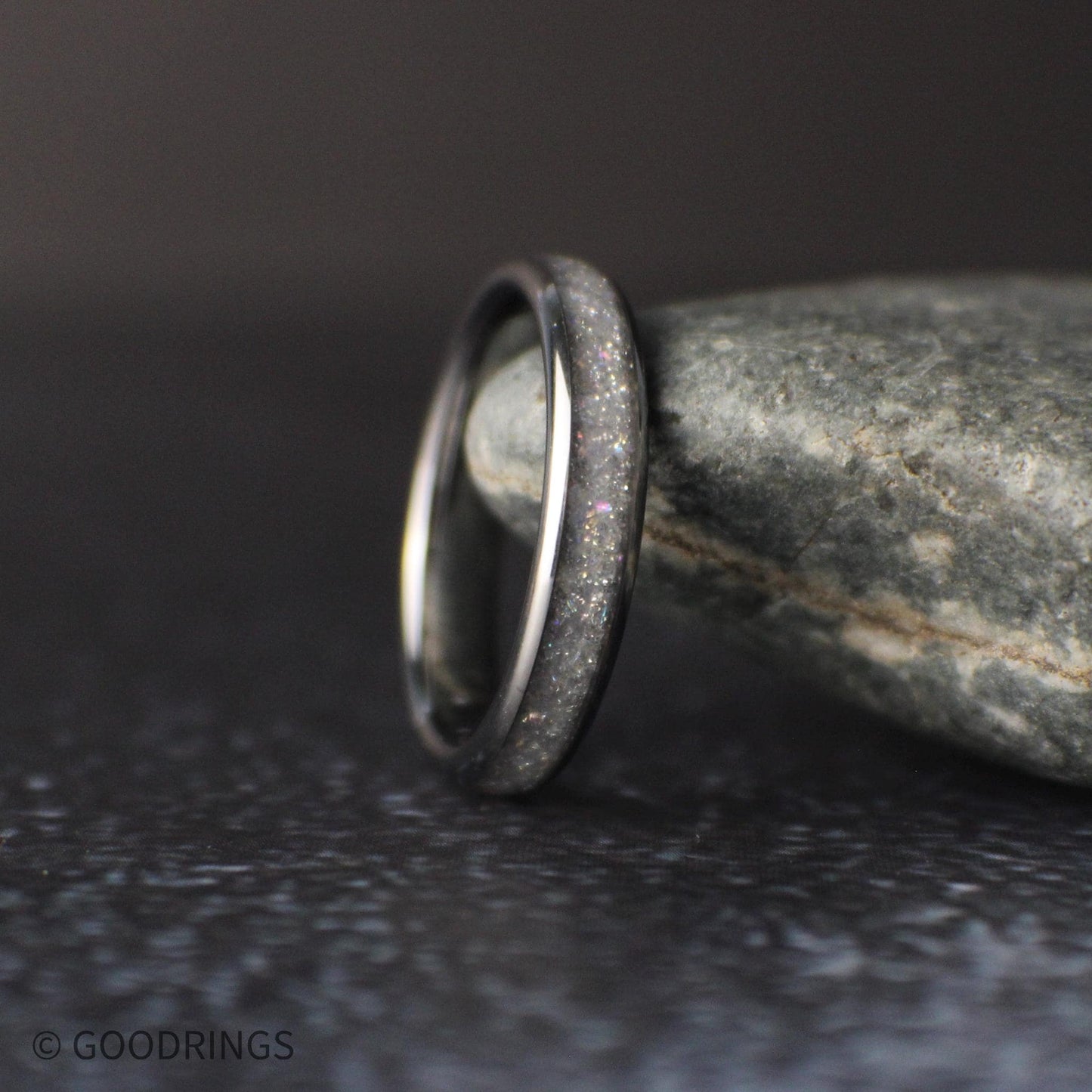 4mm tungsten ring with crushed moonstone inlay standing upright against a natural stone background with soft lighting