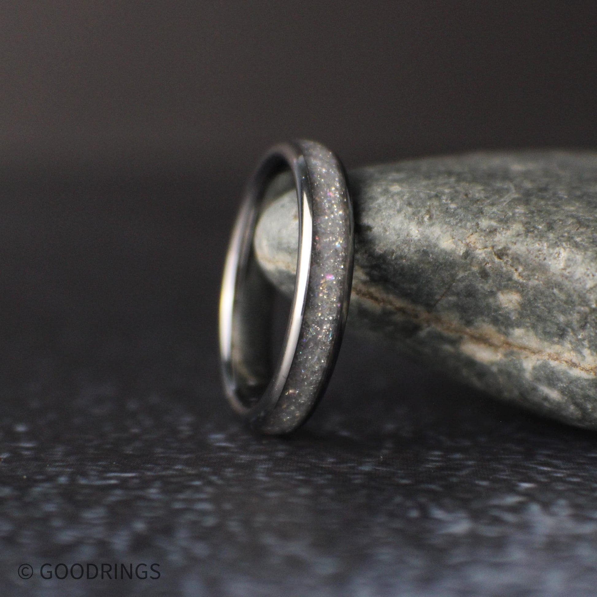 4mm tungsten ring with crushed moonstone inlay standing upright against a natural stone background with soft lighting