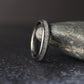 4mm tungsten ring with crushed moonstone inlay standing upright against a natural stone background with soft lighting