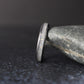 side profile of thin moonstone ring showing polished edges and sparkling crushed inlay on dark textured surface