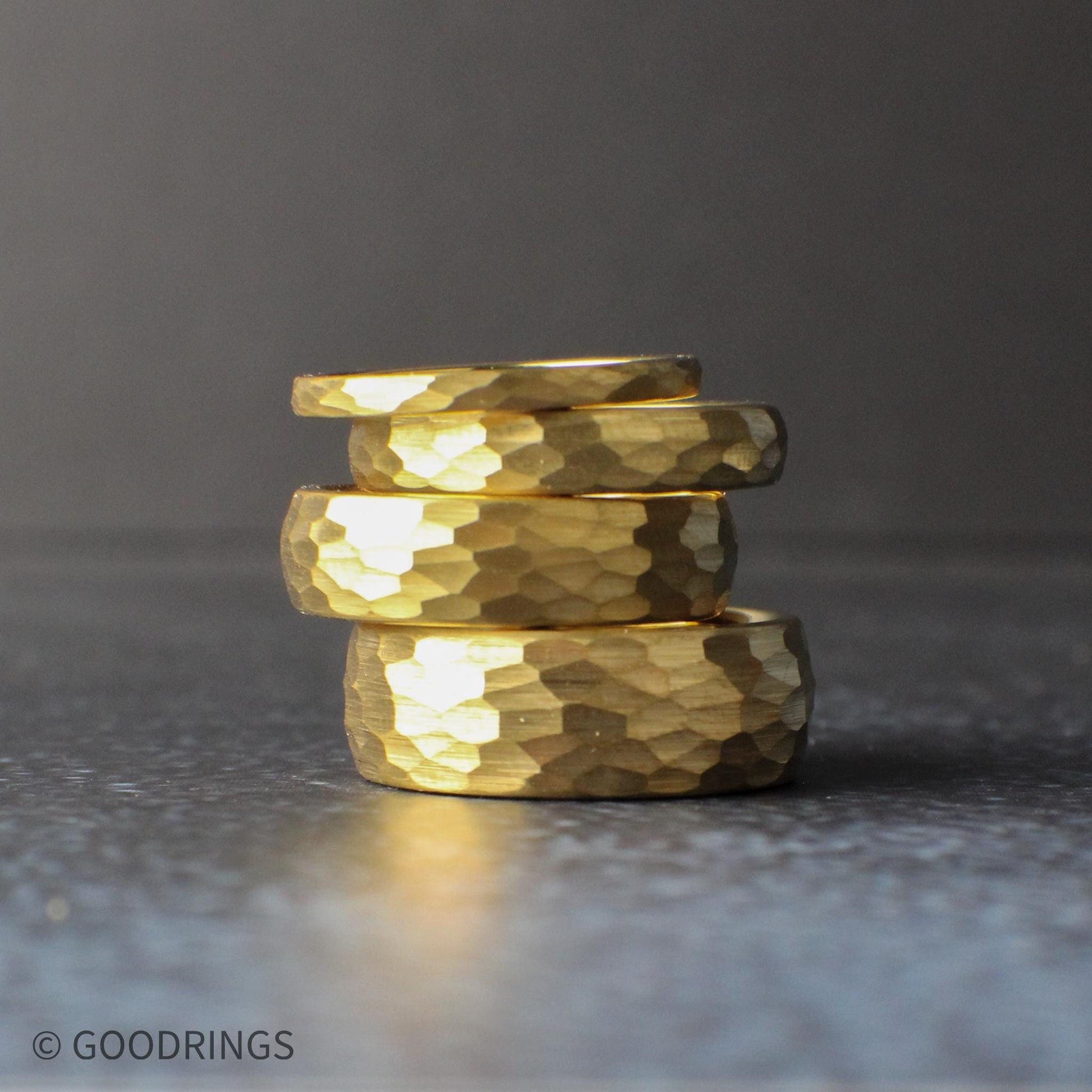 Close-up of a hammered gold tungsten wedding band showing detailed texture and light reflection across the surface. This domed 18K gold plated ring highlights the unique hammered finish, offering a strong, scratch-resistant tungsten core and a warm gold tone ideal for men’s wedding bands, women’s rings, and everyday minimalist jewelry.