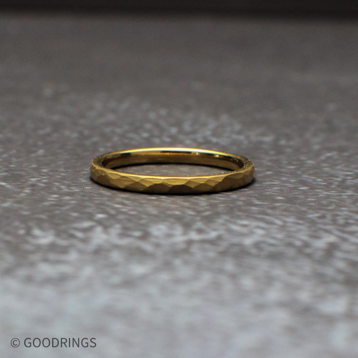 Close-up detail of the hammered texture on a gold tungsten ring, highlighting the faceted surface that catches light from every angle. This 18K gold plated band combines durability with visual depth, making it a standout choice for wedding bands and everyday rings.
