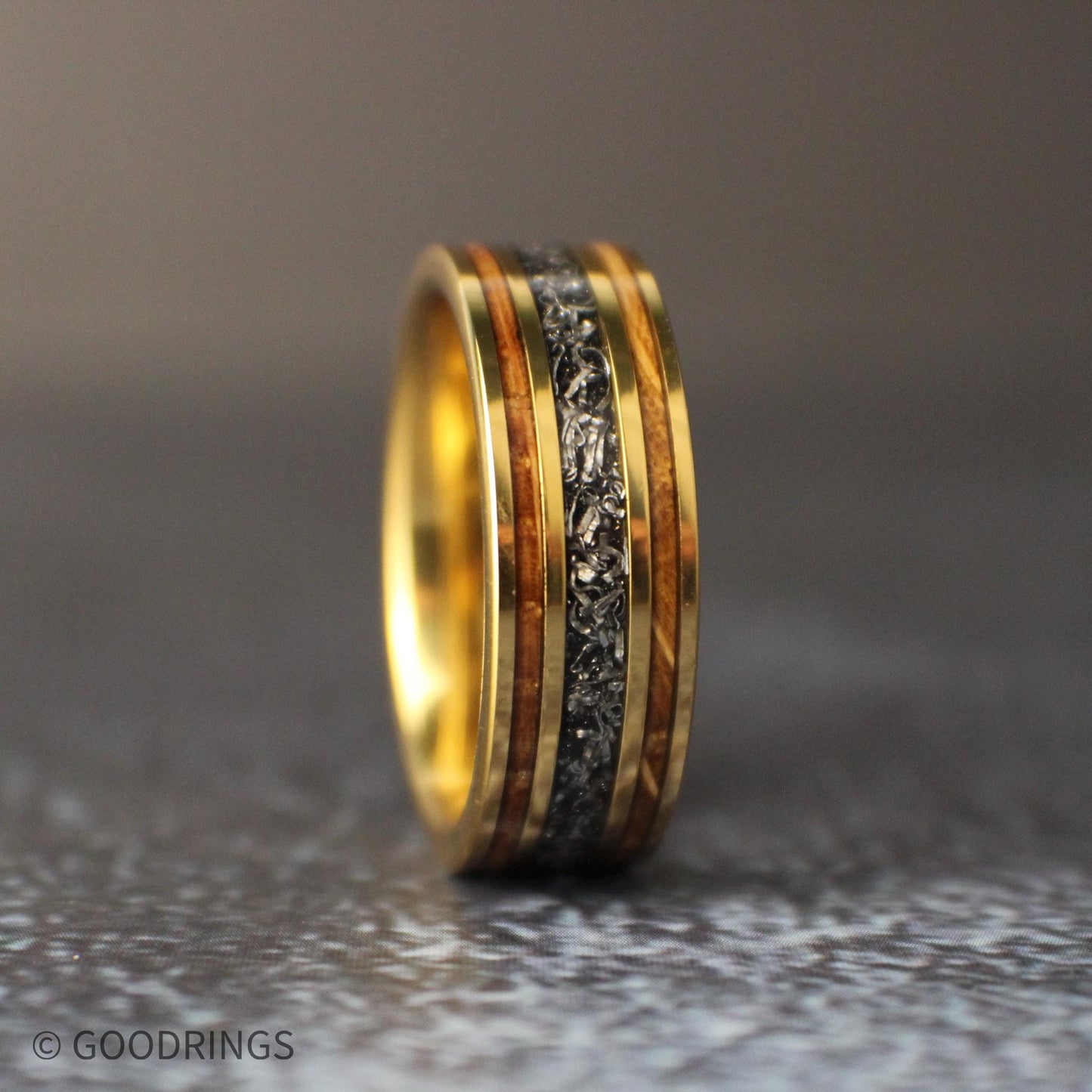 Mens wedding band standing straight up on textured tile
