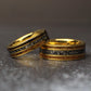 Picture of an 8mm wide gold ring with a 6mm wide gold ring leaning on it. The rings are made out of gold, tungsten, meteorite, and whiskey barrel wood.