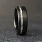 Close-up of a black tungsten wedding ring with textured genuine silver leaf inlay and modern brushed black finish.