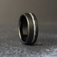 Black tungsten men’s wedding band with an offset silver leaf channel, brushed matte finish, and rounded comfort fit edges.