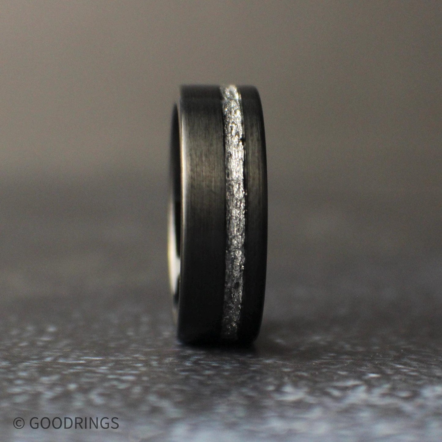 8mm black tungsten wedding band with brushed matte finish and silver leaf inlay channel, photographed on a dark background.
