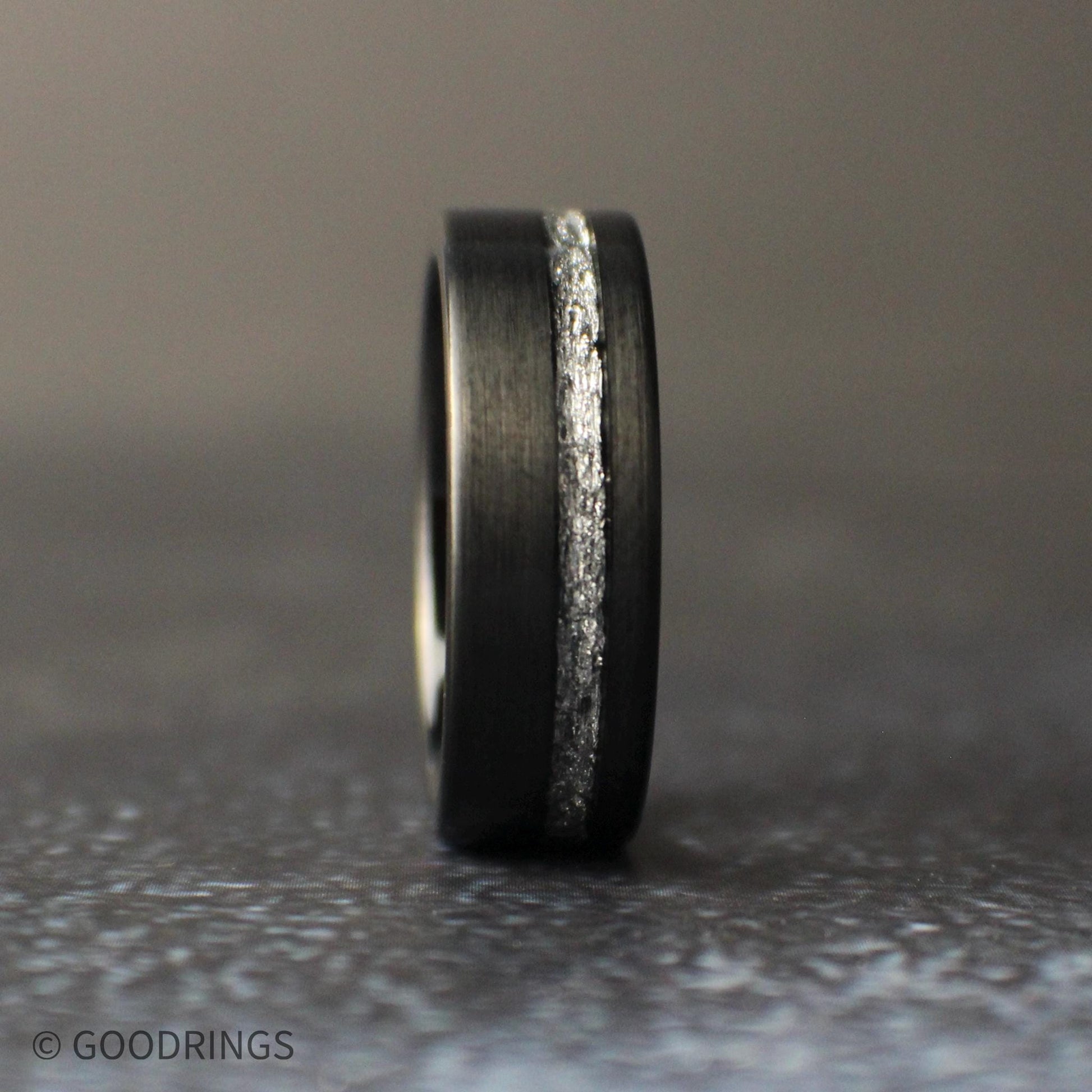 8mm black tungsten wedding band with brushed matte finish and silver leaf inlay channel, photographed on a dark background.