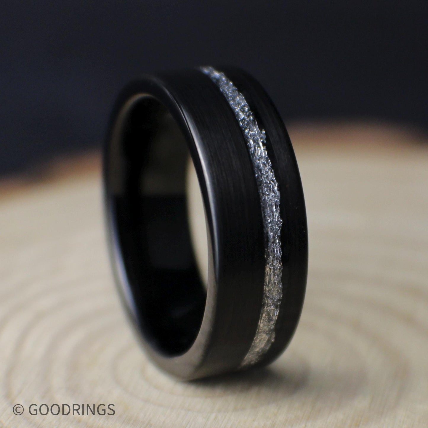 Angled close-up of an 8mm black tungsten men’s ring showing its brushed finish, comfort fit interior, and silver leaf inlay.