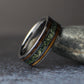 Front view of a men’s gunmetal tungsten wedding band standing upright, displaying its wide moss agate center inlay and two narrow whiskey barrel wood stripes.