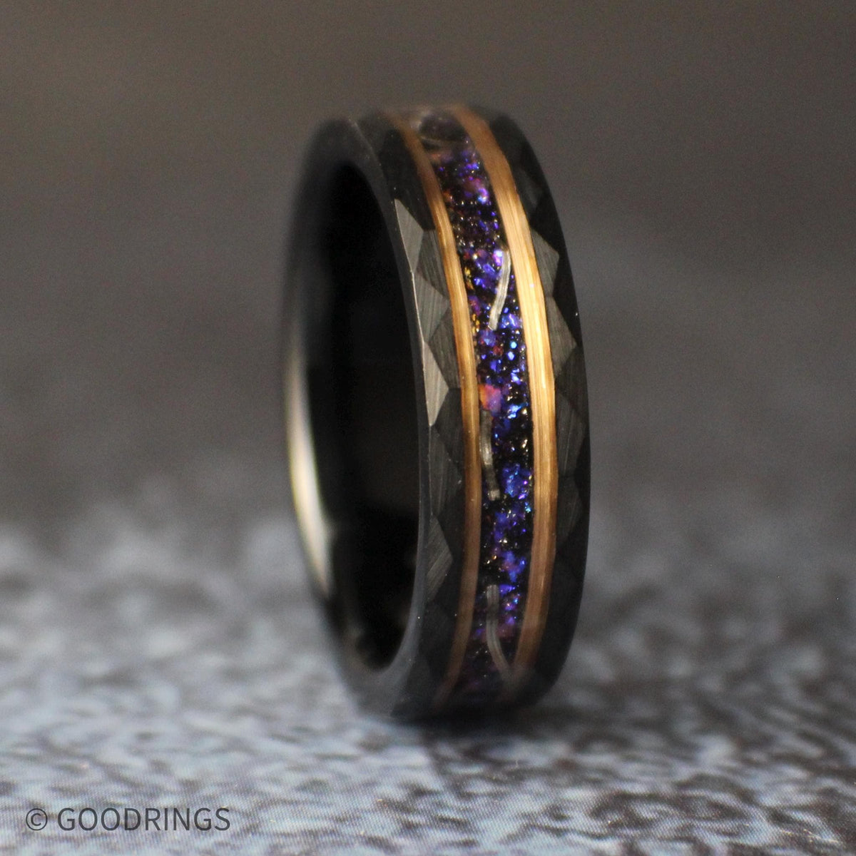 Low angled view of the black tungsten ring lying on its side, displaying the galaxy-inspired center inlay and faceted geometric edges.