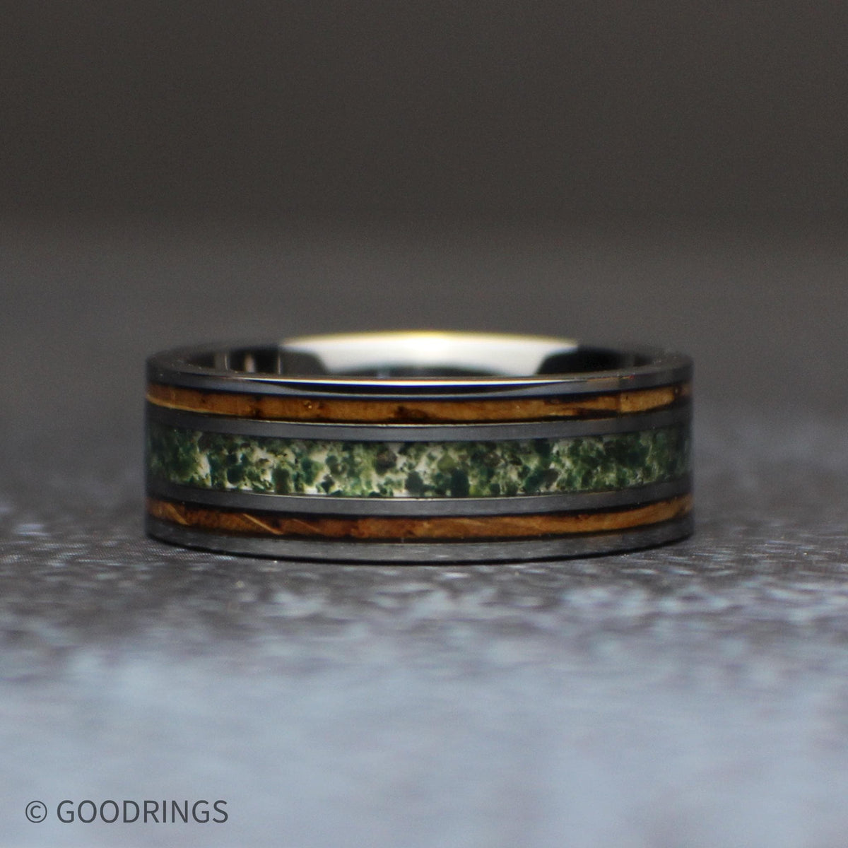 Wedding band made out of tungsten, charred whiskey barrel wood, and moss agate laying down horizontally
