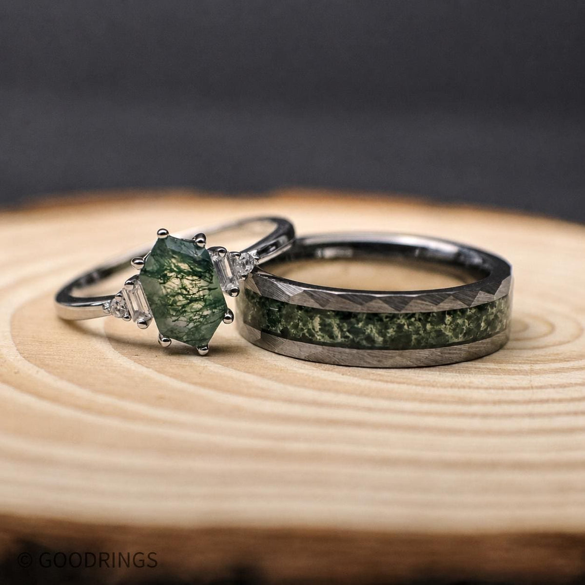 couples wedding band set with moss agate, sterling silver, and tungsten. The female ring is laying on the mens ring