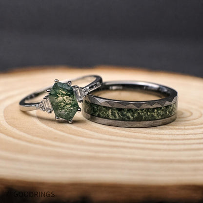 couples wedding band set with moss agate, sterling silver, and tungsten. The female ring is laying on the mens ring