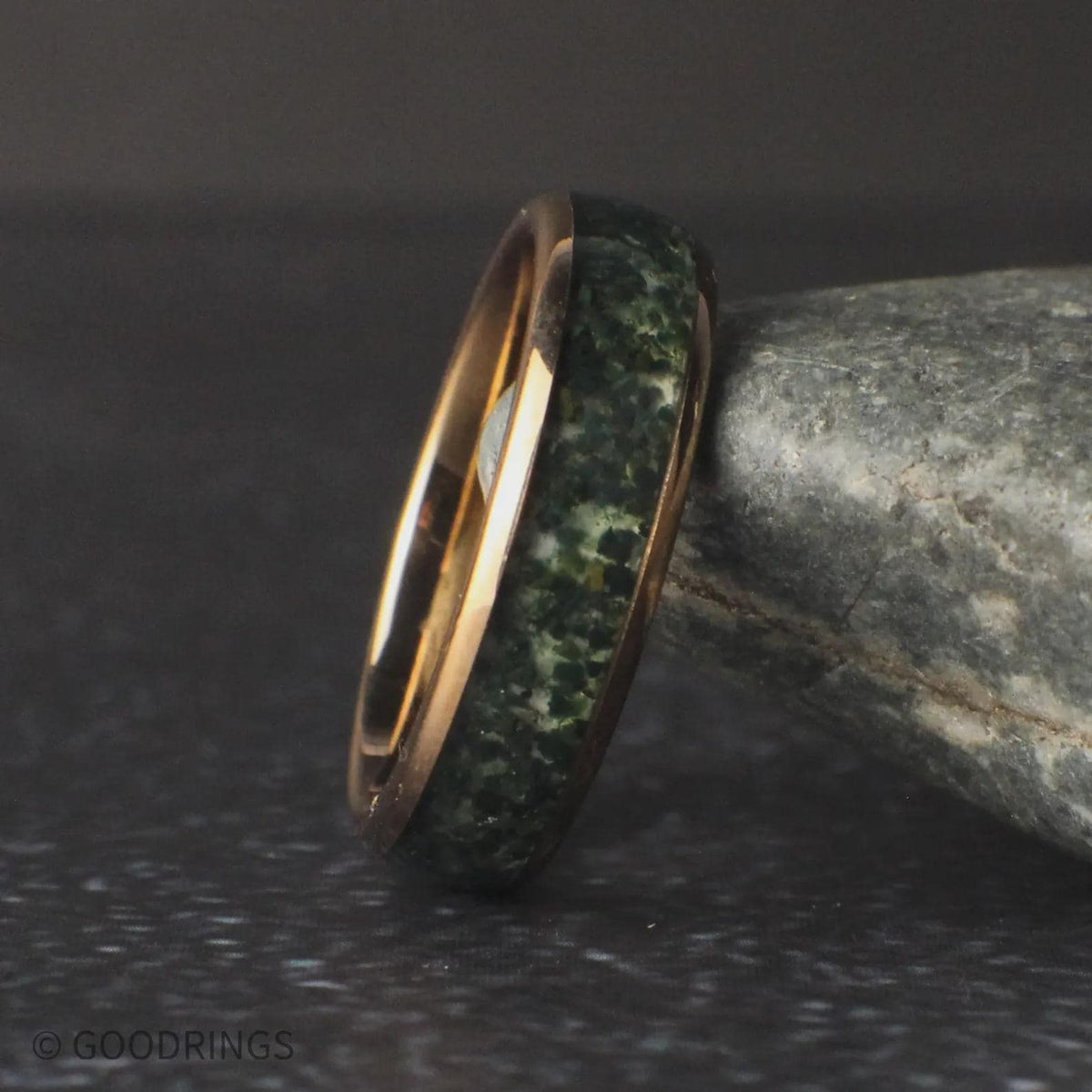 6mm wide moss agate ring leaning against a rock
